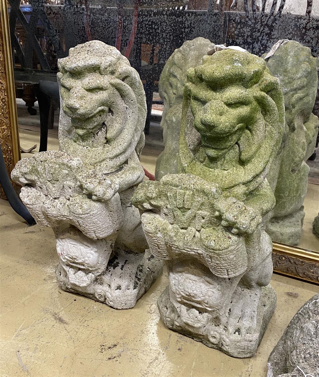 A pair of reconstituted stone lion and shield garden ornaments, height 56cm